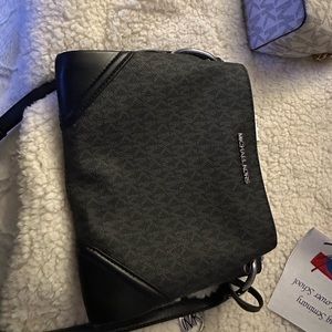 Black logo Michael Kors one zip center plus two snap close sections.